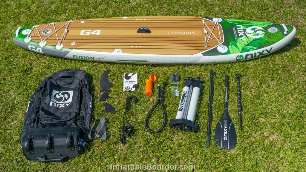 Palm-colored NIXY Newport G4 with accessories, including bag, 3 fins, pump, paddle, leash, repair kit, manual, and compression strap.