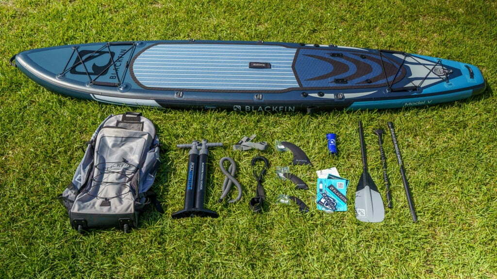 Overview of the Model V's accessory bundle: includes color-matched bag, pump, SUP leash, color-matched paddle, 3 fins, repair kit, compression strap, manual, warranty card, and sticker pack.