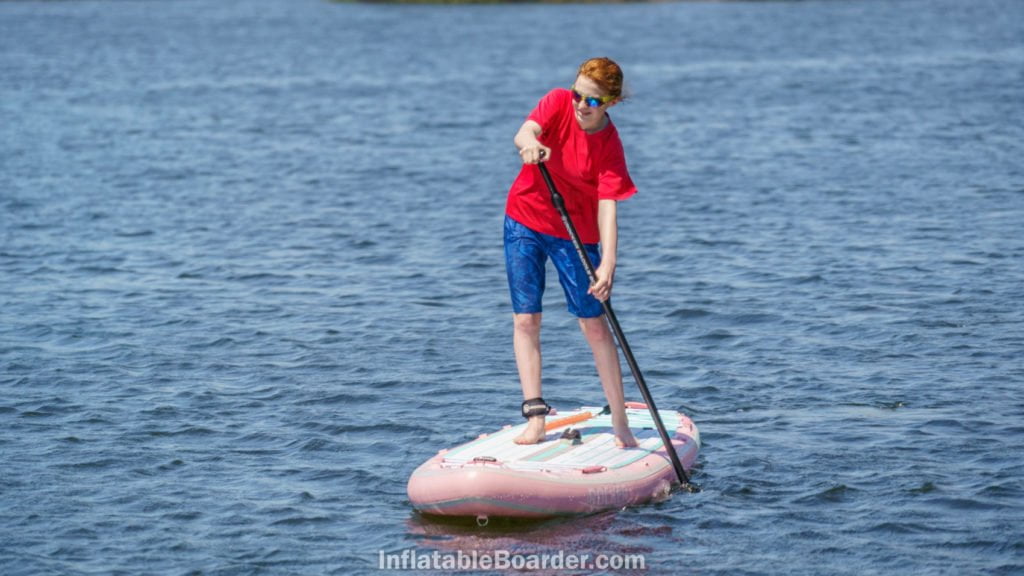 A teen paddling the SUP on open water.