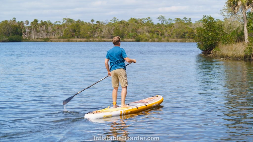 Paddling the board on calm water towards shore.