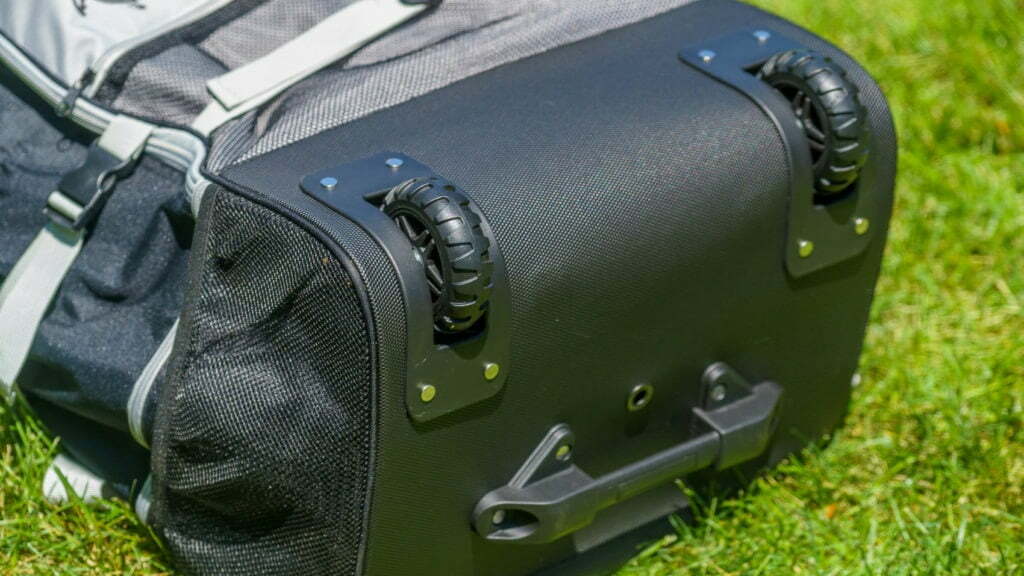 The bag has two large rugged wheels, a handle, and a drain hole.