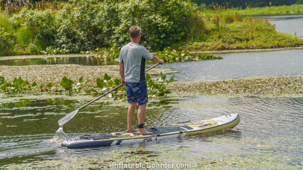 Paddling the Meno 11'6 on a calm pond with lily pads.