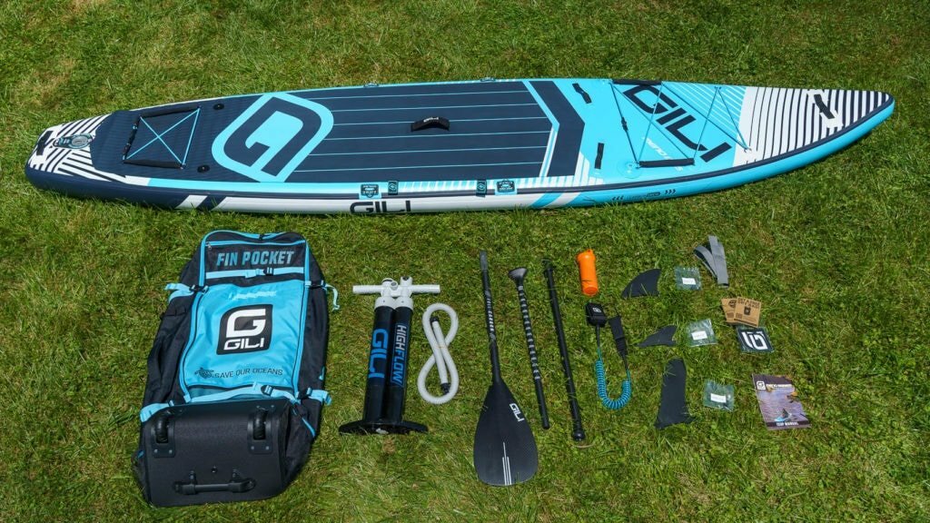 Unboxing the blue GILI Meno 12'6, featuring premium cag, dual chamber pump, carbon fiber paddle, SUP leash, 3 fins, repair kit, compression strap, and document package.