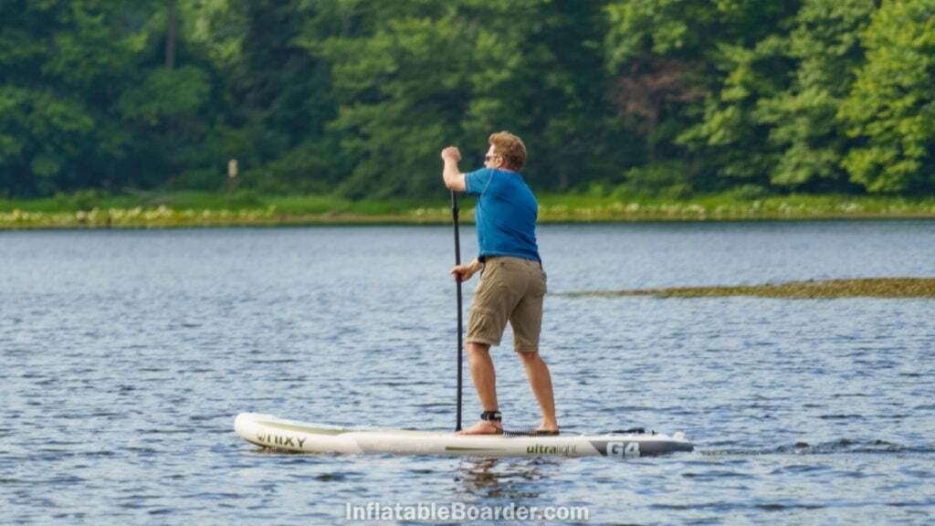 Side view of paddling the SUP on a lake.